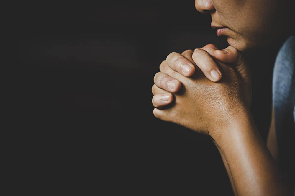Person with hands folded, deep in prayer.